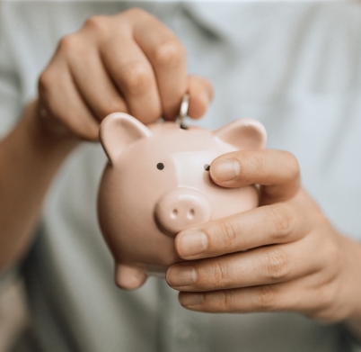 Woman hands hold a pink piggy bank and coin puts. Saving money or savings, investment concept