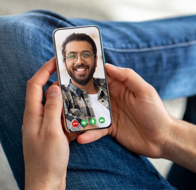 Unrecognizable Man Using Mobile App On Smartphone For Video Call With Arab Friend, Male Holding Smartphone With Virtual Chat Interface While Relaxing At Home, Creative Collage, Closeup